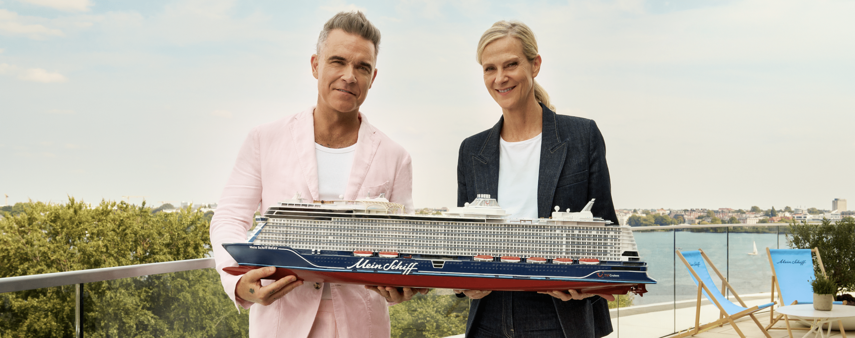 Robbie Williams mit Miniatur Mein Schiff vor See im Hintergrund